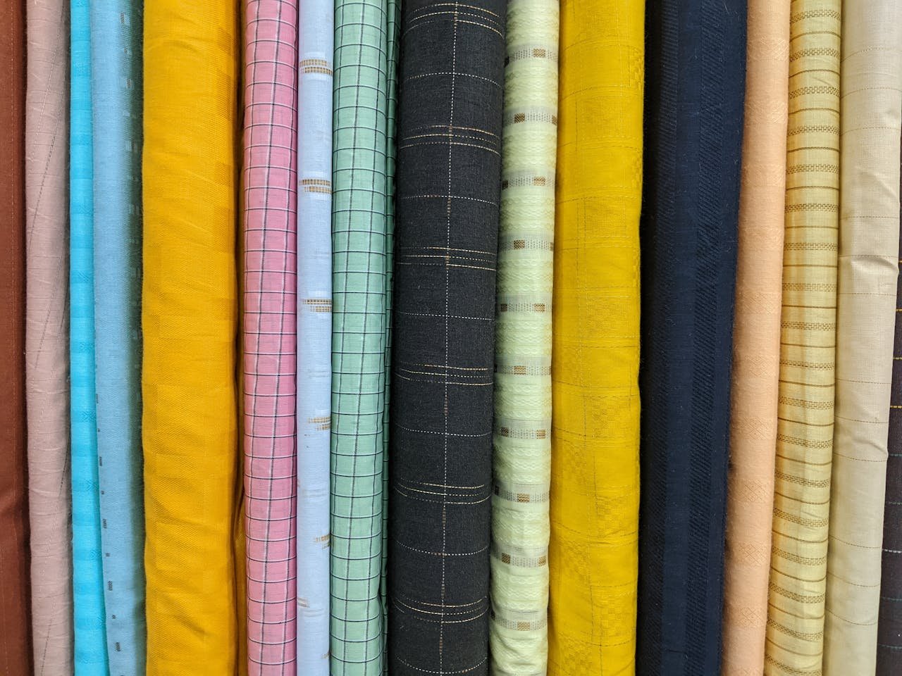 Vibrant multi-colored fabric rolls showcasing various patterns and textures in a textile store.