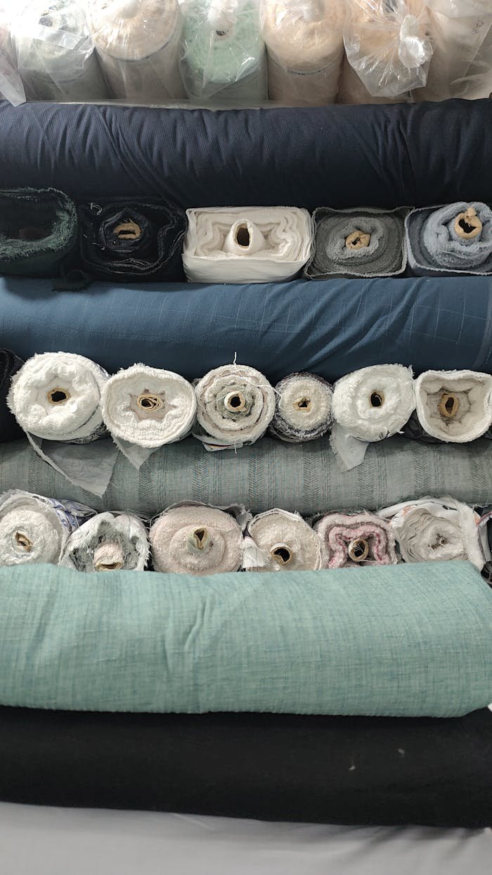 Various fabric rolls stacked in a textile store, showcasing diverse colors and textures.