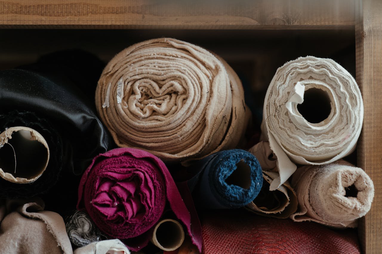 A selection of vibrant fabric rolls neatly arranged in a textile workshop setting indoors.