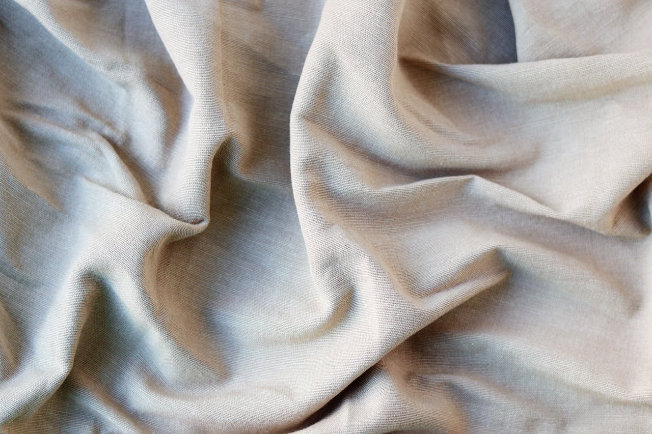 Detailed close-up of light brown crumpled cotton fabric, showcasing its texture and folds.